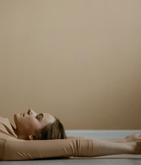 Woman in a peaceful yoga pose against a soft purple background.